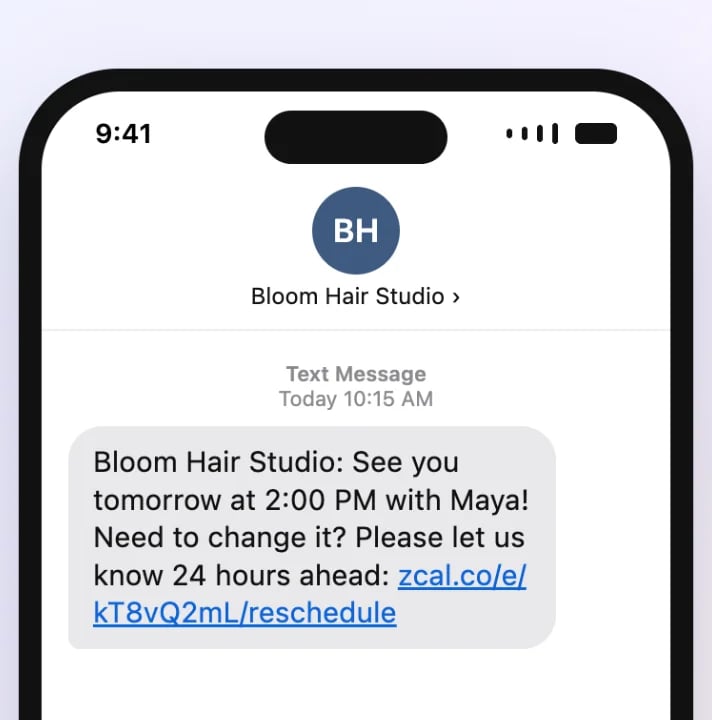 An appointment reminder text on a phone from Bloom Hair Studio: see you tomorrow at 2 PM with Maya, with a link to reschedule