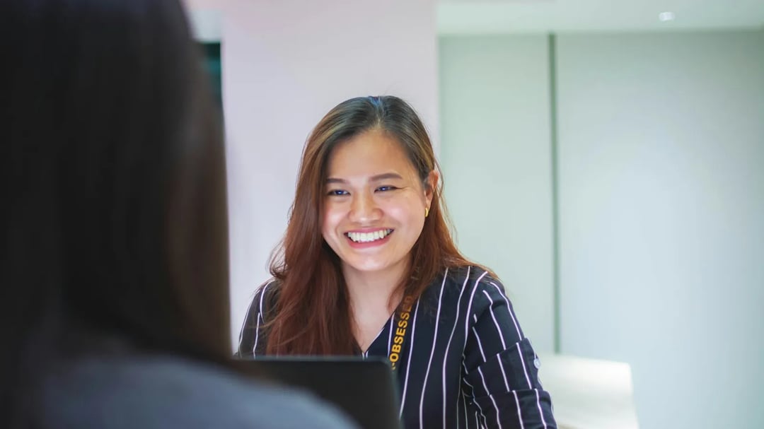A receptionist smiling at a client across the front desk