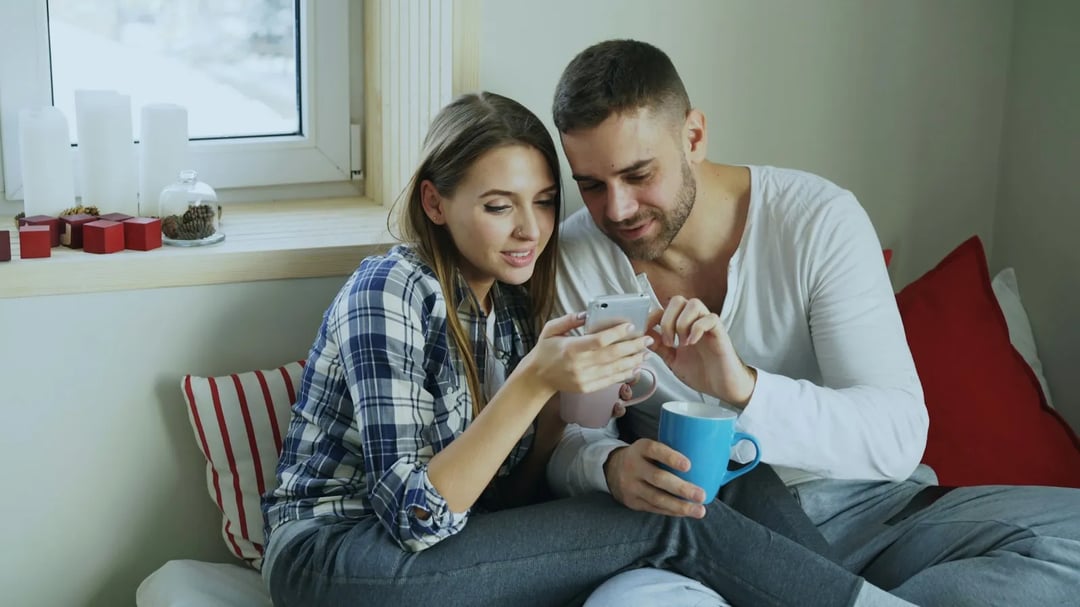 Een stel op een bank dat samen naar een telefoon kijkt