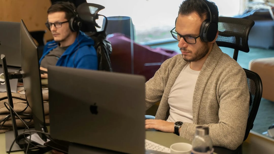 Twee teamleden met headsets aan het werk aan hun bureau